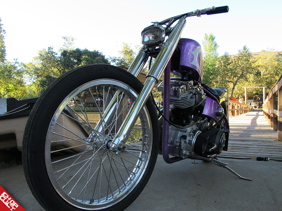 A close up of the bike's front tire also displaying the bike's fork, headlight, and handlebars