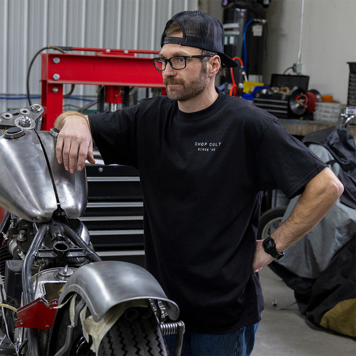 Man leaning on motorcycle wearing black shirt
