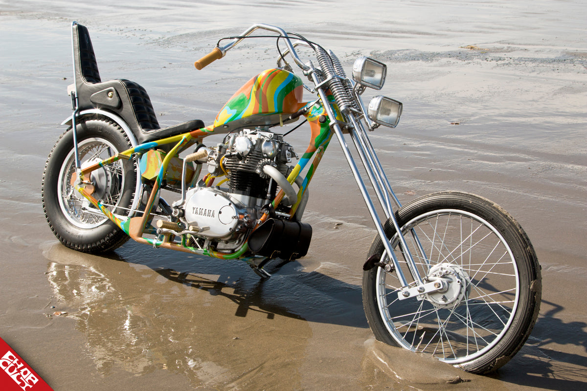 A photo of the orange, green, yellow, and blue patterned bike on the beach